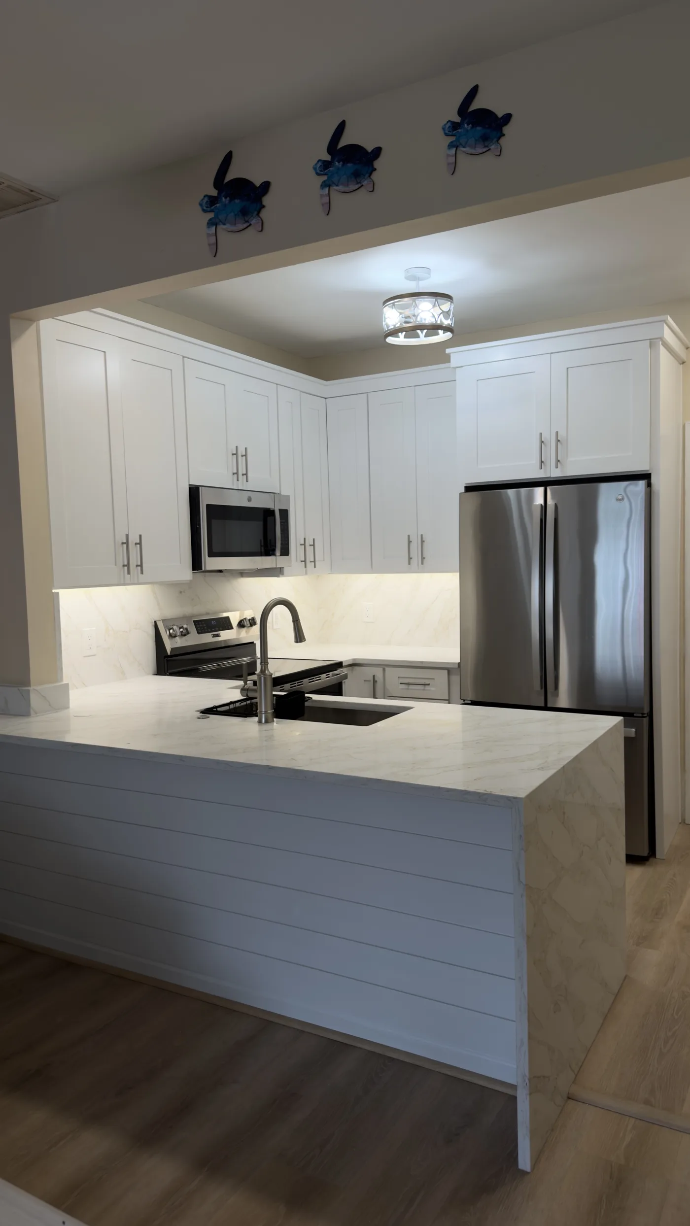 White kitchen with an island and stainless steel appliances